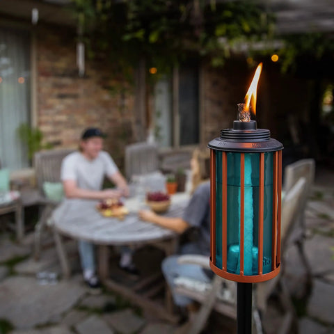 Retro Stripe Glass Torches 2 Pack 65 Inch Outdoor Patio Garden Torches Easy Install With Refillable Canisters Long Lasting Wicks Snuffer Blue And Copper shown lit on patio