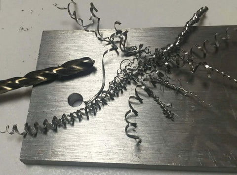 Cobalt twist drill bit on a steel plate with spiraled metal shavings