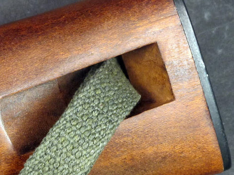 Close-up of OD green webbing through rifle stock for M1 Carbine Web Sling OD Green One Inch Canvas Reproduction With Lift-The-Dot Closure WWII Style Steel Fixtures