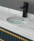 A modern bathroom countertop with built-in washbasin and sleek black faucet. White marble design complements the minimalist look.