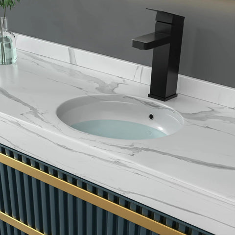 A modern bathroom countertop with built-in washbasin and sleek black faucet. White marble design complements the minimalist look.