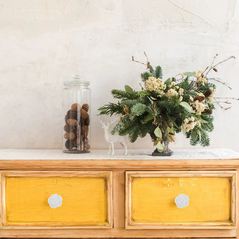 Wooden dresser with yellow drawers featuring white ceramic rose flower cabinet pull handles with screws, elegant retro design.