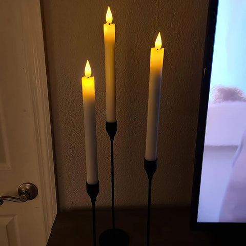 Three eight inch ivory flameless taper candles on stands, displaying realistic flickering flame and real wax look in dim lighting.