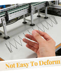Hand holding Two Pack Industrial Trapezoidal Flat Compression Springs 1x9.5x35x160mm against machinery background