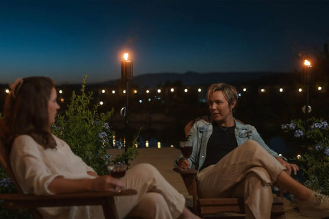 Two people enjoying a backyard evening with Mesa Torch 3 Pack Outdoor Backyard Torches With 5 Hour Burn Time In Cold Rolled Steel glowing.
