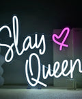 Neon sign reading 'Slay Queen' with a heart symbol on an acrylic base, white and pink LED lighting.