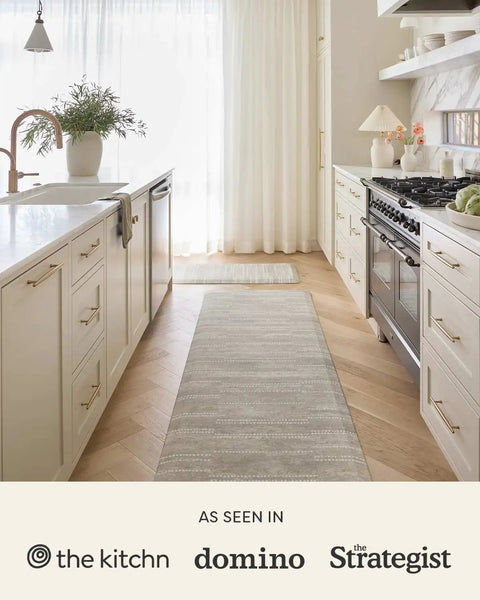 Kitchen with long gray rug runner, beige cabinets, and modern appliances.