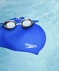 Blue swim cap with goggles in a pool; Go-To Unisex Silicone Swim Cap For Adults, No-Snag, Stretchy, Hair-Friendly Cap That Protects Hair From Chlorine