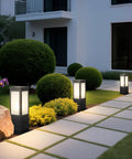 Rock Solid 15.75 Inch Outdoor Bollard Path Lights With Knockout Aluminum Frame And Frosted Glass Shade illuminating a garden pathway.
