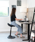 Woman using Ultra Slim Single Top Standing Desk Riser Height Adjustable Sit Stand Converter for Monitor in home office.