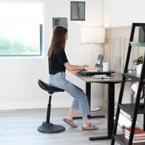 Woman using Ultra Slim Single Top Standing Desk Riser Height Adjustable Sit Stand Converter for Monitor in home office.