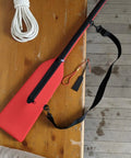 Red Pro Grade Paddle Bag For Boats With Quick Rapid Evaporation Tech on wooden table, showing strap and neoprene material.