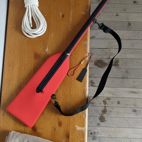 Red Pro Grade Paddle Bag For Boats With Quick Rapid Evaporation Tech on wooden table, showing strap and neoprene material.