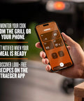 Person holding phone showing app interface for controlling Woodridge Pro Electric Wood Pellet Grill And Smoker For Backyard Grillin