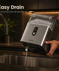 Top Tier Countertop Nugget Ice Maker Churns Out 35 Pounds Of Chewable Pebble Ice In Just Seven Minutes With Self Cleaning Design And Removable Basket For Everyday Chill Sessions In Silver draining into a sink.