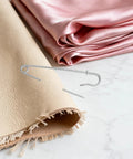 Rugged Heavy Duty Iron Safety Pins Pack Of 50 for securing thick leather and silk fabrics on a marble surface.