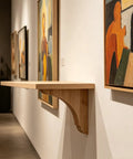 Wooden shelf with sturdy wood triangle shelf brackets for floating shelves wall mounted in art gallery with paintings
