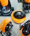 Heavy Duty 4 Inch Polyurethane Caster Wheels Set Of 4 Swivel Casters With Dual Lock Brakes close-up view of casters showing orange wheels and mounting hardware.