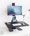 Heavy Duty Electric Standing Desk Converter With Monitor Mount And Wide Keyboard Tray, Black desktop setup with monitor and device holders.