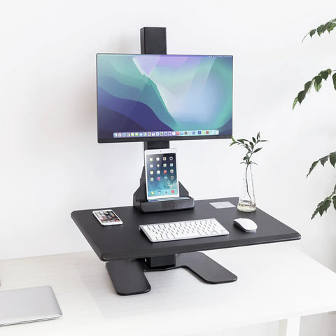 Heavy Duty Electric Standing Desk Converter With Monitor Mount And Wide Keyboard Tray, Black desktop setup with monitor and device holders.