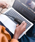 Person using 256GB USB 3.1 Type C External SSD Drive Portable Solid State Storage Up To 500MB Per Second For PC Mac Android Game Console And More Ideal For Photo Video Backup And On The Go connected to a laptop