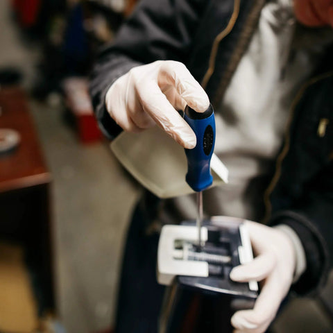 GLOVEWORKS HD ivory latex disposable gloves, large, powder-free, worn while using a blue-handled screwdriver on equipment