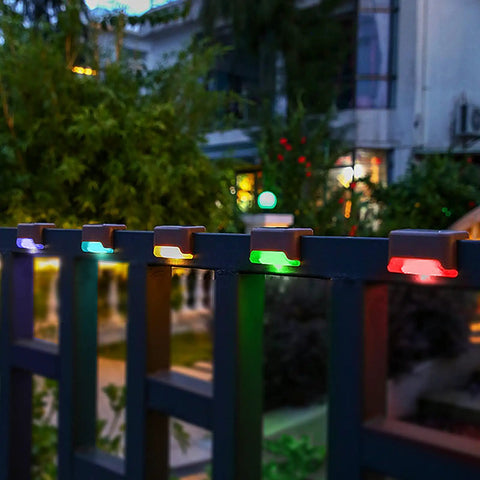 16 Pack Solar Deck Lights Outdoor Color Changing LED Waterproof Pathway Lights For Stairs Patio Yard Garden Fence Porch Decor With Romantic RGB Glow installed on a fence.