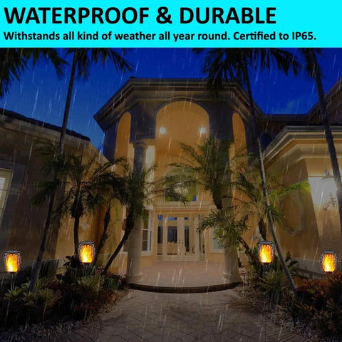 Two Pack Upgraded Solar Torch Lights With Realistic Dancing Flame LEDs 96 LED Dusk To Dawn Flicker 42.9 Inch Tall Outdoor Waterproof Garden Path Lighting For Patio Walkways illuminating a house entrance at night.