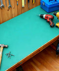 Green rubber ESD anti-static mat on a workshop bench with hammer and drills.