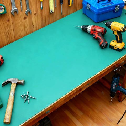 Green rubber ESD anti-static mat on a workshop bench with hammer and drills.