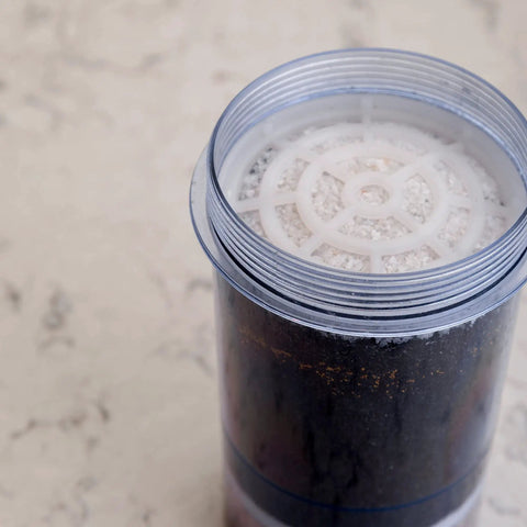 Replacement Filter For Gravity Water System That Reduces Fluoride And Chlorine, clear cylindrical filter on countertop