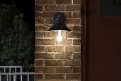 Orion Outdoor Solar Wall Light With 150 Lumen Warm White LED At 2700K on brick wall at night, black resin sconce