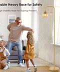 Modern Floor Lamp With Amber Glass Globe Shade And 6W LED Bulb next to family in living room, brass gold finish and safe base