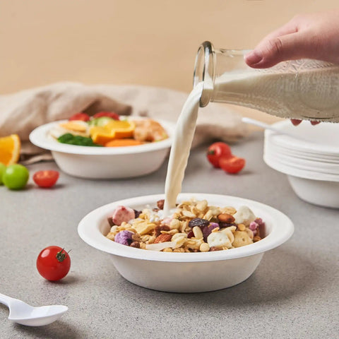 Hand pouring milk into 16 oz sugarcane bagasse soup bowl from 175 Pack 16 Oz Sugarcane Bagasse Soup Bowls Microwave Safe Heavy Duty Disposable For Hot Soups Desserts And Snacks Eco Friendly Compostable Dinnerware, surrounded by fresh fruits.