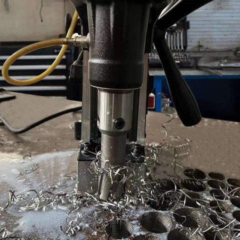 Close-up of S&F Stead & Fast magnetic drill press kit cutting into metal, with spiraled metal shavings around the bit.