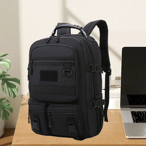 Black rugged hiking backpack for outdoor adventures and weekend trips, daypack travel pack on desk next to laptop