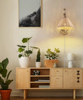 Rattan Wrapped Wall Sconce With Adjustable Swing Arm And Foldable Vintage Bedside Light Gold Finish With Wicker Shade Plug In Or Hardwire Brass Reading Lamp For Living Room Or Bedroom in living room setting.