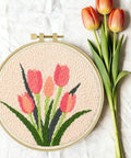 Punch Needle Embroidery Kit Beginner Friendly Two Pack With Tools Embroidery Hoops Two Pre Printed Fabrics And Color Threads Flower Pattern Set Tulip Bouquets And Sunflower Clusters DIY Home Decor Gift Project featuring tulip bouquet design in embroidery hoop with real tulips beside it