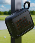 Magnetic Shockproof Case For JBL GO 4 Speaker Liquid Silicone Cover attached to metal with outdoor golf course in background.