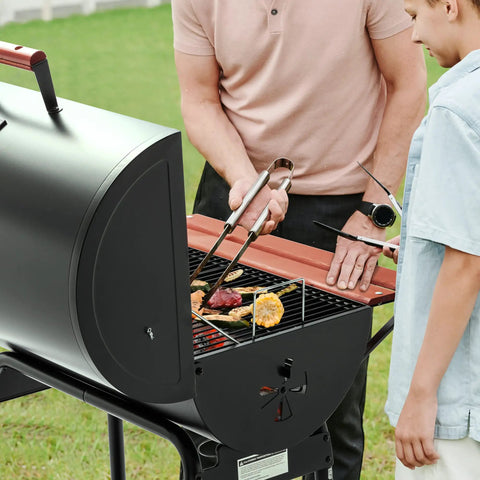 Two people grilling on a 30 Barrel Charcoal Grill With Wood Painted Side Front Table And 627 Sq In Cooking Space For Backyard BBQs, Outdoor Parties, And Patio Grilling, For Backyard Parties And Weekend Cookouts, Black in the backyard