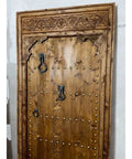 Natural Finish Hand Carved Barn Door In Rustic Solid Wood with ornate carvings and studs, 71x34in, custom size interior door