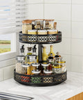 Two-tier black metal rotating Lazy Susan spice organizer on kitchen counter with glass jars.