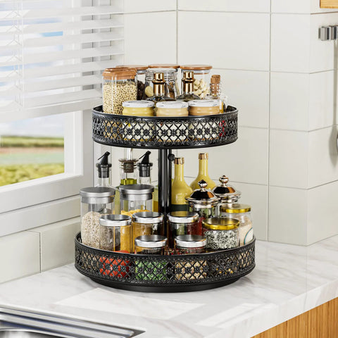 Two-tier black metal rotating Lazy Susan spice organizer on kitchen counter with glass jars.