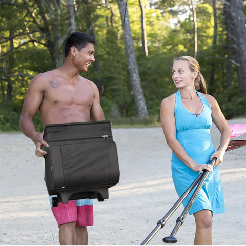 Rolling Cooler With Wheels And Handle 29 Liter 50 Can Capacity Portable Soft Leakproof Insulated Wheeled Cooler held by man at beach.