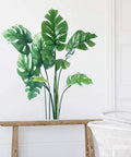 Monstera wall decals for living room and bedroom decor featuring tropical plants vinyl mural on white wall with wood bench.