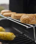 Propane Grill For Outdoor Cooking And BBQ With 2 Burners Black Finish Porcelain-Enameled Cast Iron Grates And Snap-Jet Ignition Ready To Grill Like A Pro with buns and corn on the warming rack.
