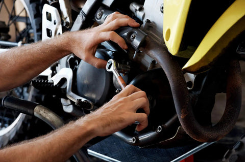 Hands using Essenti-Economy Motorcycle Tool Kit for Harley-Davidson and V-Twin Hybrids, Fits Most Fork Bags for repairs.