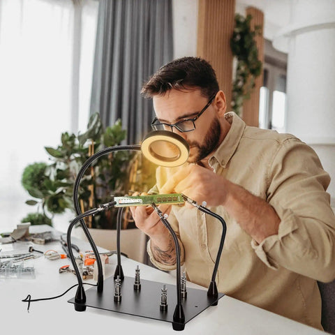 Helping Hands Soldering Clamp Station with 6X LED Magnifying Lamp, person soldering a PCB with flexible metal arms and weighted base.