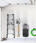 Badass Heavy Duty Garage Storage Hooks hold ladder, shovel, cart, and hose on wall for organized tool storage.