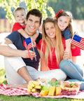 Family holding 40 Pack Small American Flags On Sticks 4 By 6 Inch Mini Flags for 4th of July, picnic setting, kid-safe wooden sticks